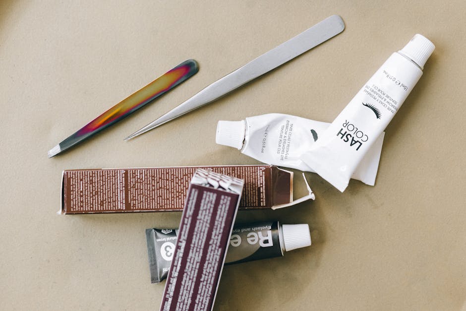 Flat lay of eyelash tint and beauty tools on a beige surface, ideal for salon promotions.