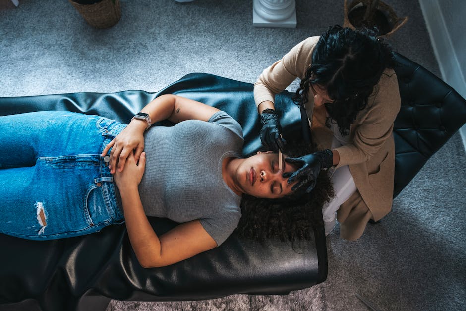 A woman receiving a skincare facial treatment from an esthetician in a modern spa environment.