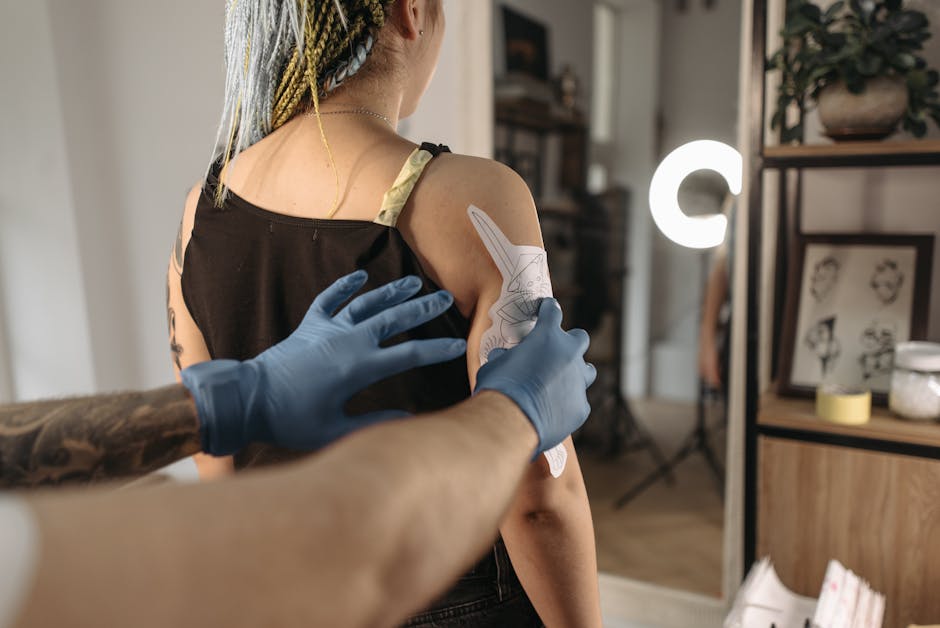 Tattoo artist applying stencil to client's arm in studio setting. Professional tattooing process.