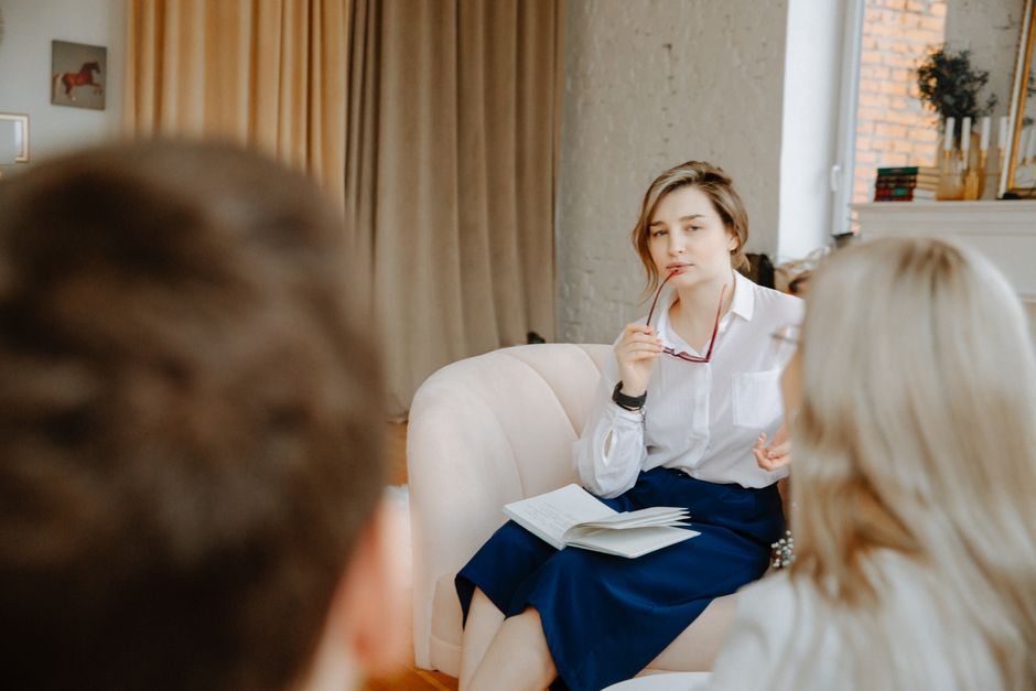 Counselor in a therapy session, attentively listening to clients indoors.