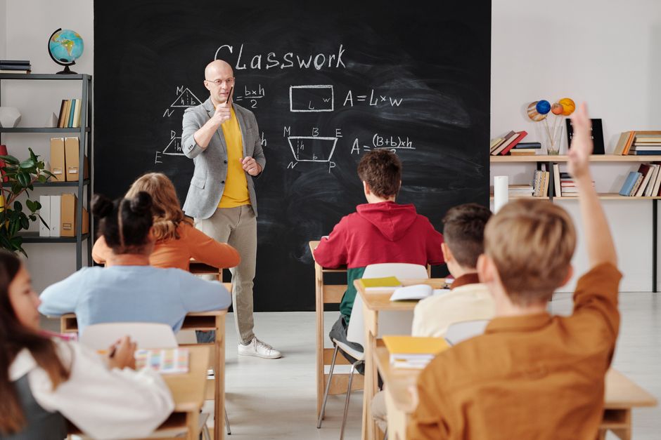 Ein Lehrer erklärt Geometrie, während Schülerinnen und Schüler in einem modernen Klassenzimmer aufmerksam folgen.